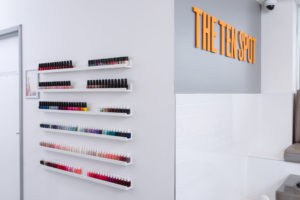 wall with nail polish bottles and THE TEN SPOT logo in orange lettering