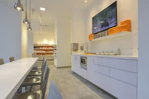 THE TEN SPOT beauty bar with manicure tables, sinks, a TV and orange towels