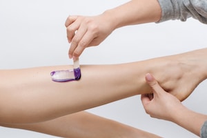 woman getting her leg waxed with purple wax