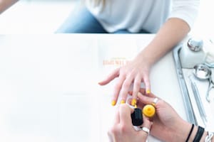woman getting her nails painted with yellow nail polish