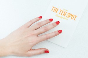 a women with red painted nails next to a TEN SPOT brochure