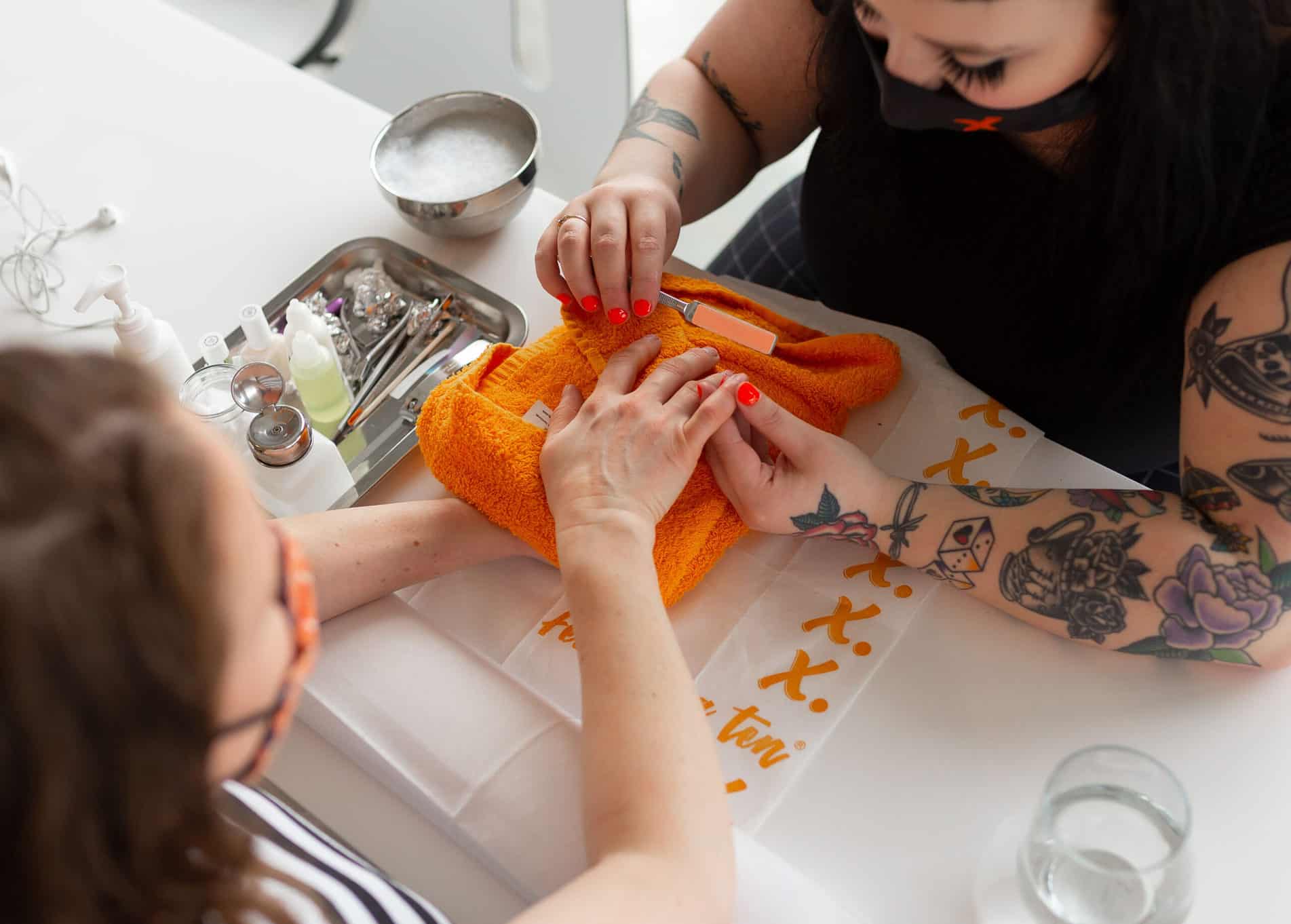 woman getting her nails filed with an orange file and orange towel